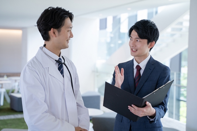 お互い笑顔で商談している男性医師と男性営業職