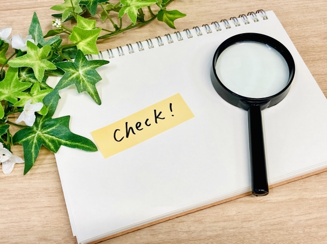 デスクにある虫眼鏡と「check」と書かれた付箋のイラスト
