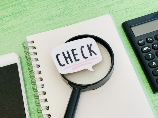 デスクにある虫眼鏡と「CHECK」と書かれた吹き出しのイラスト
