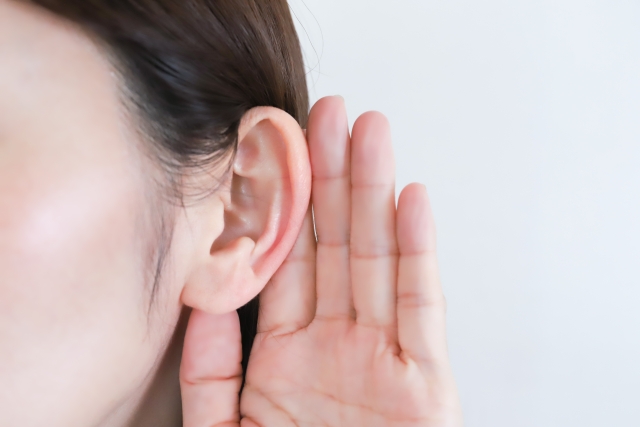 耳に手を当てて声を聞いている女性