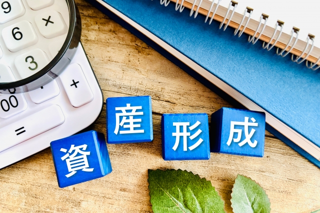 デスク上に電卓とブロックで「資産形成」の文字