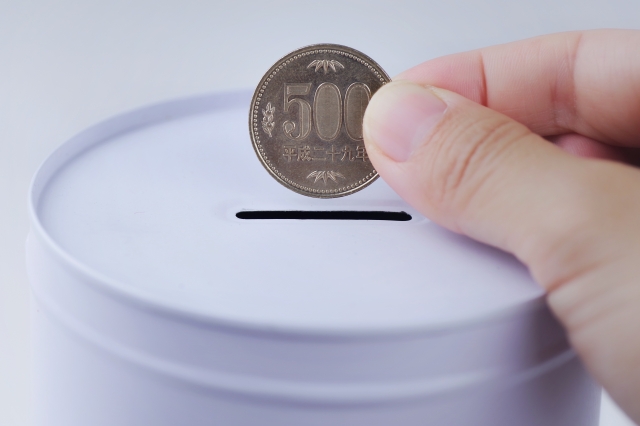 貯金箱に硬貨を入れているイラスト
