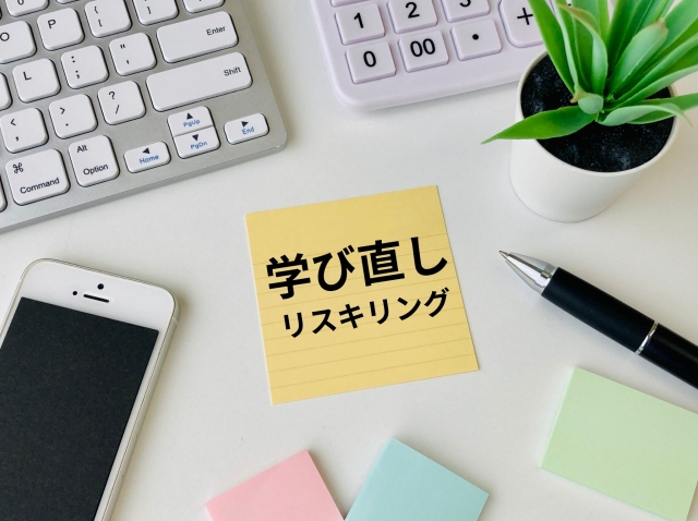 デスク上の付箋に「学び直し リスキリング」と書かれたイラスト