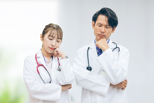 顎に手を当てて困ったポーズをする男性医師と女性医師
