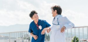 屋上で談笑するベテラン男性医師と若手男性医師