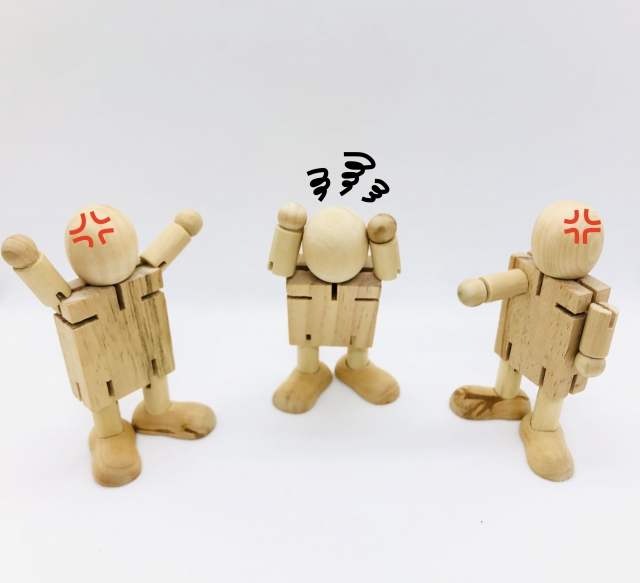 怒っている二人の板挟みになる人形のイラスト