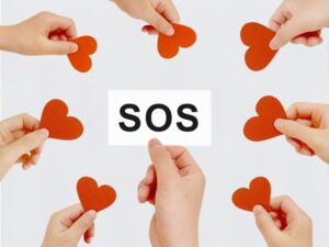 「SOS」と書かれたカードにハートマークが寄り添う画像