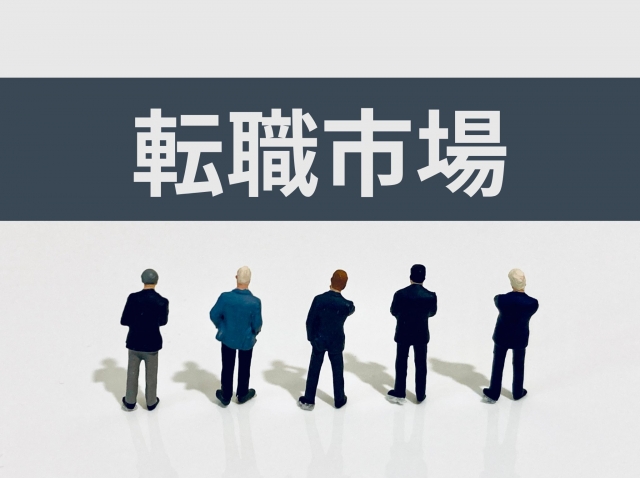「転職市場」の文字を見つめる5体のミニチュア